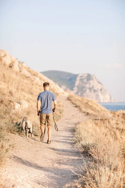 Jeune caucasien mâle marche avec chien pendant le lever du soleil — Photo