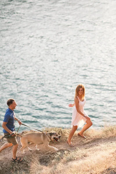 Couple of guys playing with their dog on the mountain near ocean — Stock Photo, Image