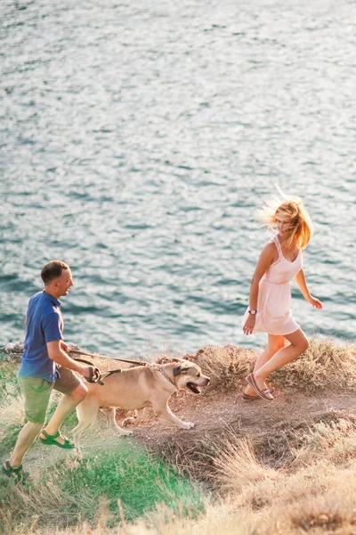 Couple of guys playing with their dog on the mountain near ocean — Stock Photo, Image