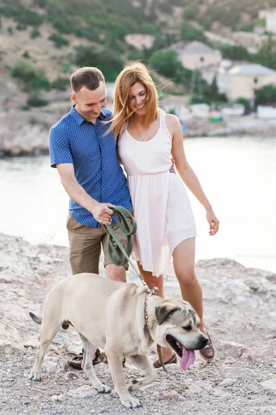 Coppia di ragazzi che giocano con il loro cane sulla montagna vicino all'oceano — Foto Stock