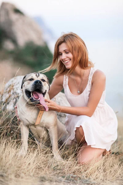 Jovem caucasiana caminhando com o cão durante o nascer do sol — Fotografia de Stock