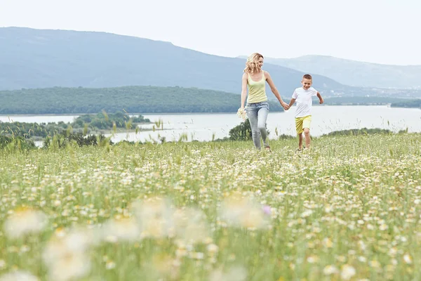 Mother having fun with his son in the blossom field of camomile — Stock Photo, Image