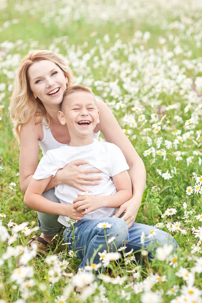 Matka, zabawy z synem w dziedzinie kwiat rumianku — Zdjęcie stockowe