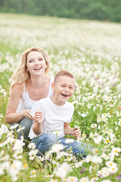 Mother having fun with his son in the blossom field of camomile — Stock Photo, Image