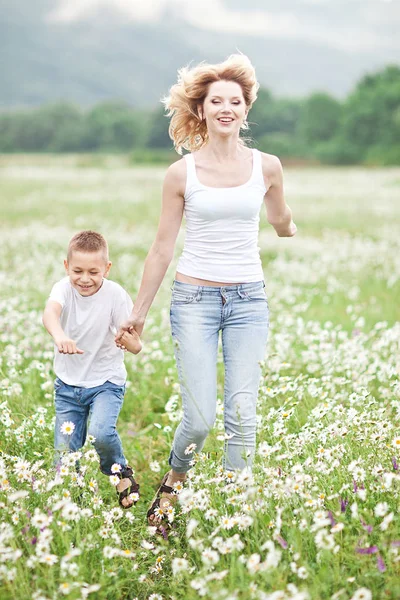 Mère s'amuse avec son fils dans le champ fleuri de la camomille — Photo