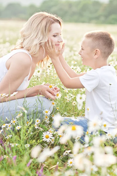 Mutter amüsiert sich mit Sohn im Blütenfeld der Kamille — Stockfoto