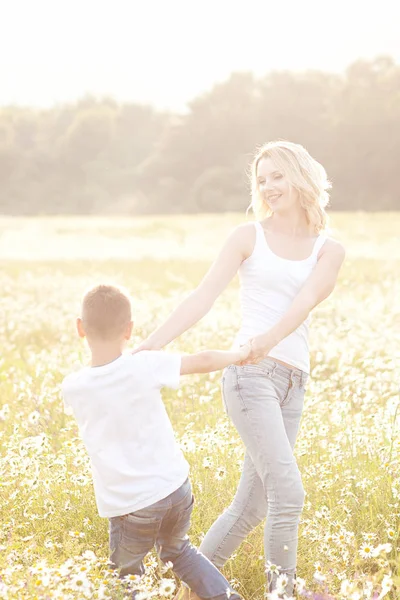 Mère s'amuse avec son fils dans le champ fleuri de la camomille — Photo