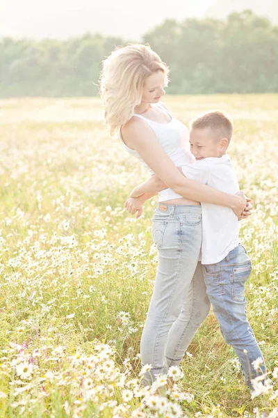 Мама веселилась с сыном на цветущем поле ромашки — стоковое фото