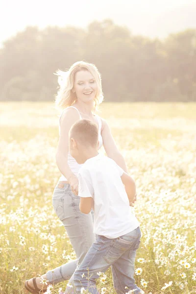 Mutter amüsiert sich mit Sohn im Blütenfeld der Kamille — Stockfoto