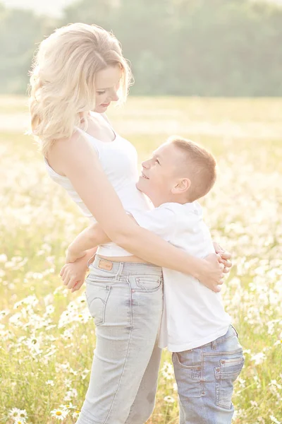 Мама веселилась с сыном на цветущем поле ромашки — стоковое фото