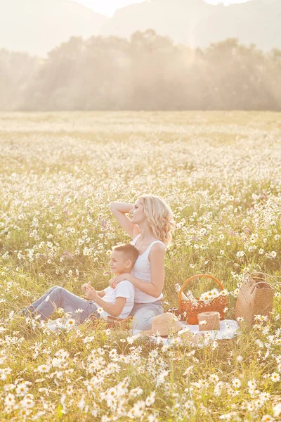 Mother having picnic with his son in the blossom field of camomi — Stock Photo, Image