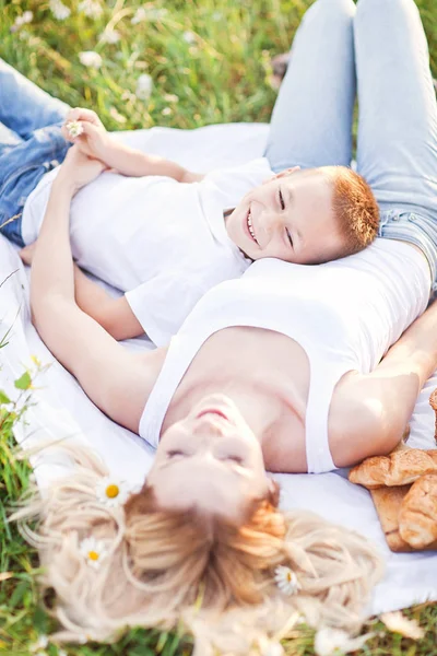 Matka pikniku z synem w dziedzinie kwiat camomi — Zdjęcie stockowe