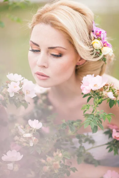 Schöne blonde Braut im weißen Kleid mit Blumen im Haar — Stockfoto