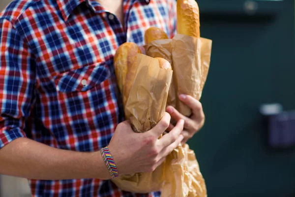 Man goes out a bakery. Take bread in his hand — Stock Photo, Image