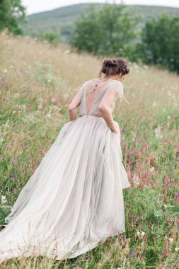 Bir buket çiçek ve yeşil ile güzel bir elbise içinde gelin