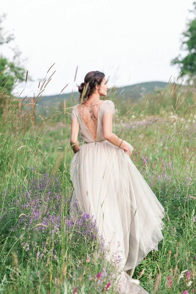 Noiva em um lindo vestido com um buquê de flores e mais verde — Fotografia de Stock