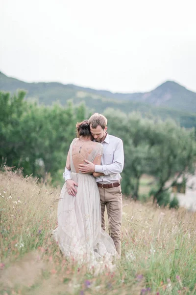 Couple en tenue de mariage avec un bouquet de fleurs et de verdure — Photo