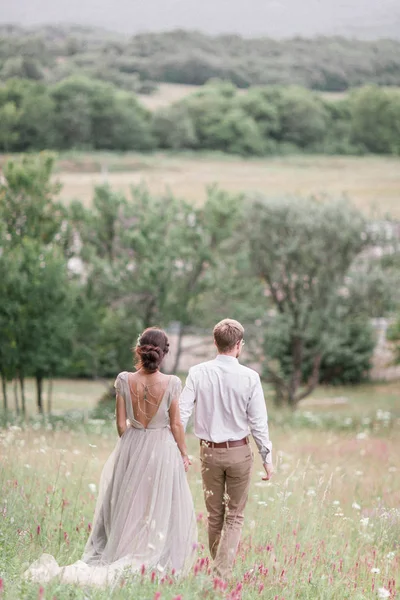 Pareja en traje de novia con un ramo de flores y vegetación —  Fotos de Stock