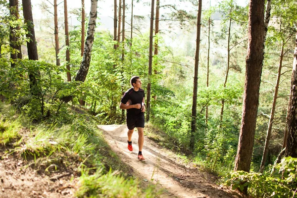 Mužské sportovce běžec běží na silnici v lese — Stock fotografie