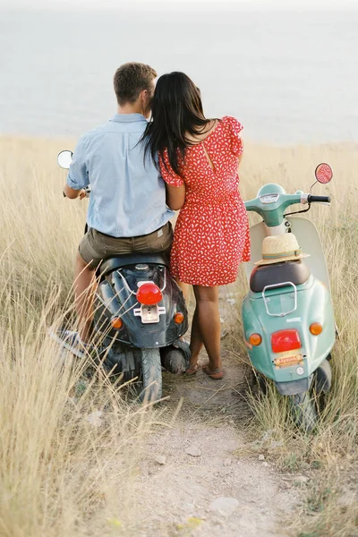 Happy young couple in love on retro motorbike driving togetger and ejoying the trip near the ocean. — Stock Photo, Image