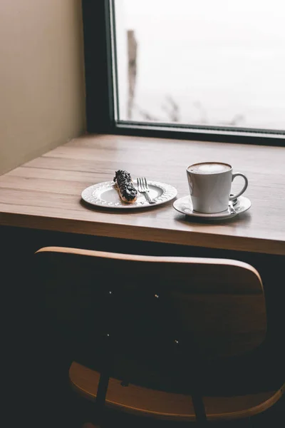 エクレールの木製テーブルの上のコーヒー カップ — ストック写真