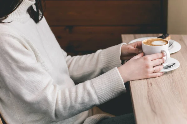 Frauenhände um eine Tasse auf Holztisch mit Schokolade gewickelt — Stockfoto