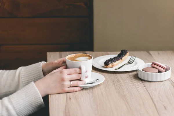 Frauenhände um eine Tasse auf Holztisch mit Schokolade gewickelt — Stockfoto