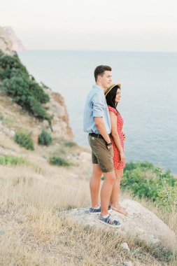 Deniz tarafından dağlarda yürüyüş aşık genç şık çift. Asma günbatımı yaz ruh hali