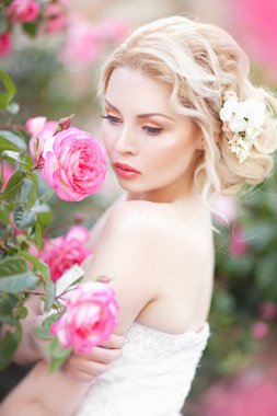 Bir çiçekli çalı güller poz bir gelinlik yakınındaki güzel esmer gelin