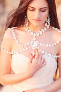 Beyaz elbise deniz kıyısında günbatımı üzerinde poz içinde genç esmer gelin