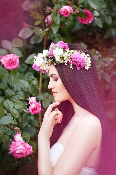 Piękna Brunetka Panna Młoda w pobliżu kwitnienia Bush róże pozowanie w sukni ślubnej — Zdjęcie stockowe