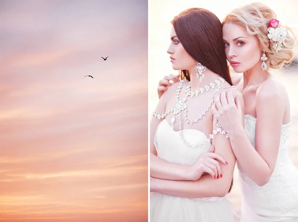 Joven dos novias en vestidos blancos posando junto al mar al atardecer —  Fotos de Stock