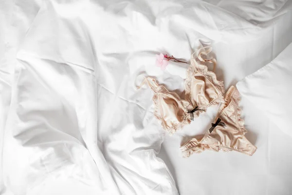 Linda roupa interior de seda lingerie encontra-se em uma cama branca — Fotografia de Stock