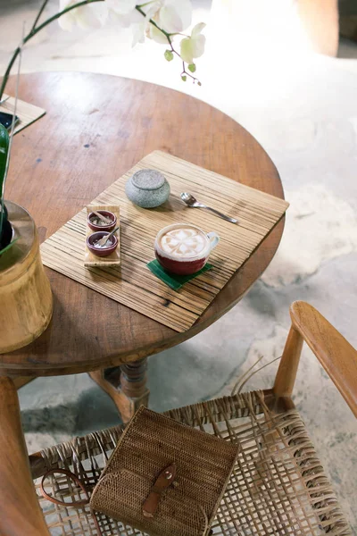 木製のテーブルにカプチーノのカップ。竹スタイル。籐のバッグ — ストック写真