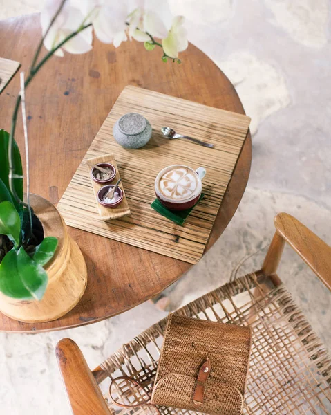 Kopje cappuccino op een houten tafel. Bamboe stijl. Rieten tas op — Stockfoto