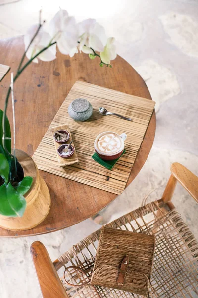Fincan kapuçino ahşap bir masa üzerinde. Bambu tarzı. Hasır çanta üzerinde — Stok fotoğraf