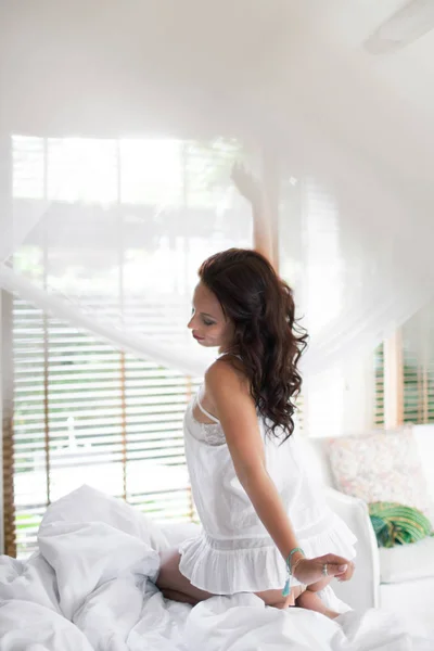 Όμορφη μελαχρινή κοπέλα ξυπνάει το πρωί στο κρεβάτι της σε Χο — Φωτογραφία Αρχείου