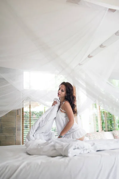 Vacker brunett flicka vaknar upp på morgonen i sin säng på ho — Stockfoto