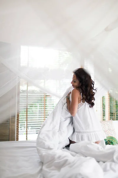 Beautiful brunette girl wakes up in the morning in her bed at ho — Stock Photo, Image