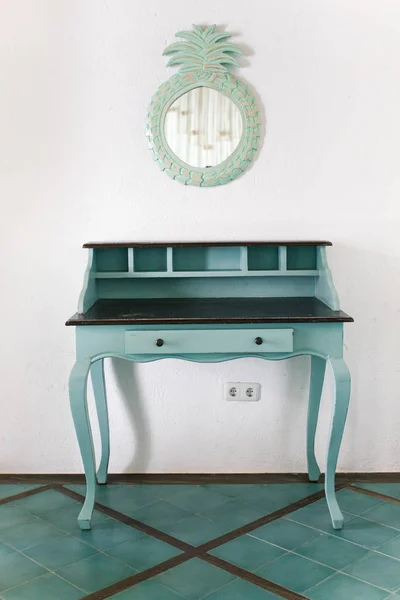 Blue vintage table of drawers stands near white wall