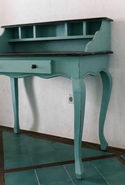 Blue vintage table of drawers stands near white wall