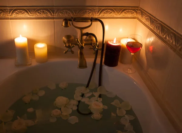 Ein Bad mit Rosenblättern und Kerzen nehmen. romantischer Abend in der — Stockfoto