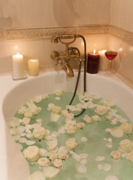 Tome un baño con pétalos de rosa y velas. Noche romántica en th —  Fotos de Stock