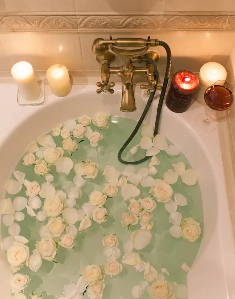 Tome un baño con pétalos de rosa y velas. Noche romántica en th —  Fotos de Stock