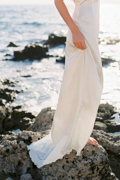 Szép szőke menyasszony fehér selyem esküvői ruhában pózol a tenger közelében — Stock Fotó