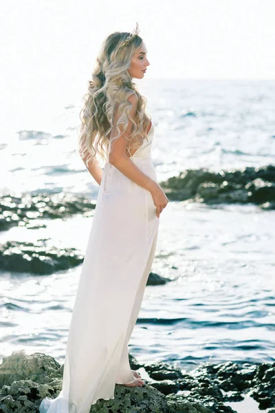 可爱的金发碧眼新娘的白色丝绸婚纱在海边摆姿势 — 图库照片