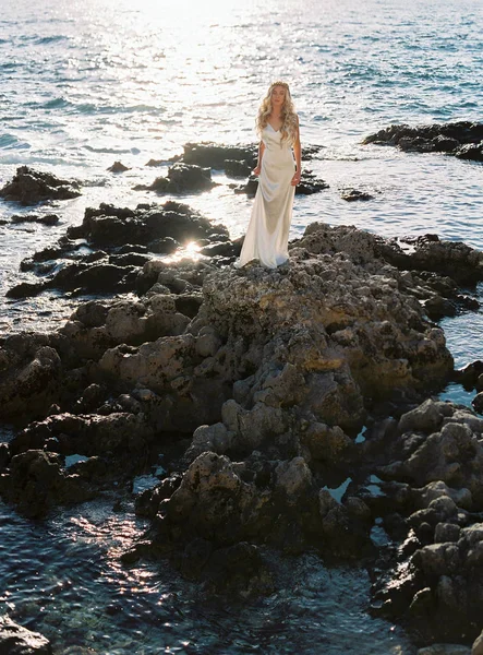 Preciosa novia rubia en vestido de novia de seda blanca posando cerca del mar —  Fotos de Stock