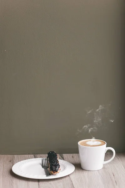 エクレールの木製テーブルの上のコーヒー カップ — ストック写真