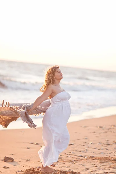 Όμορφη έγκυος γυναίκα με μακριά ξανθά μαλλιά στέκεται πάνω από το να — Φωτογραφία Αρχείου