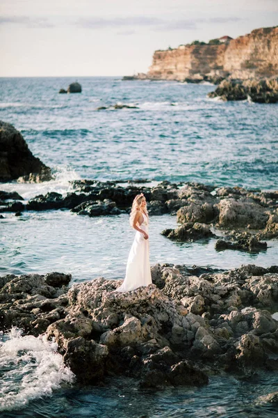 Noiva loira posando em rochas perto do mar. Fotos delicadas e sinceras. Casamento no estrangeiro. Casamento na praia — Fotografia de Stock